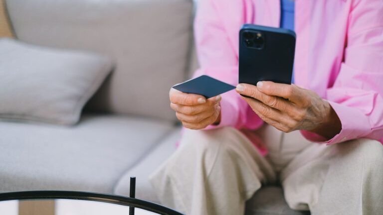 Mãos segurando celular e cartão de banco antes de fazer uma transferência