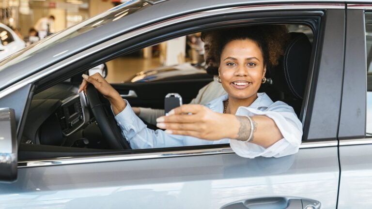 Mulher sorrindo dentro do carro novo, segurando a chave